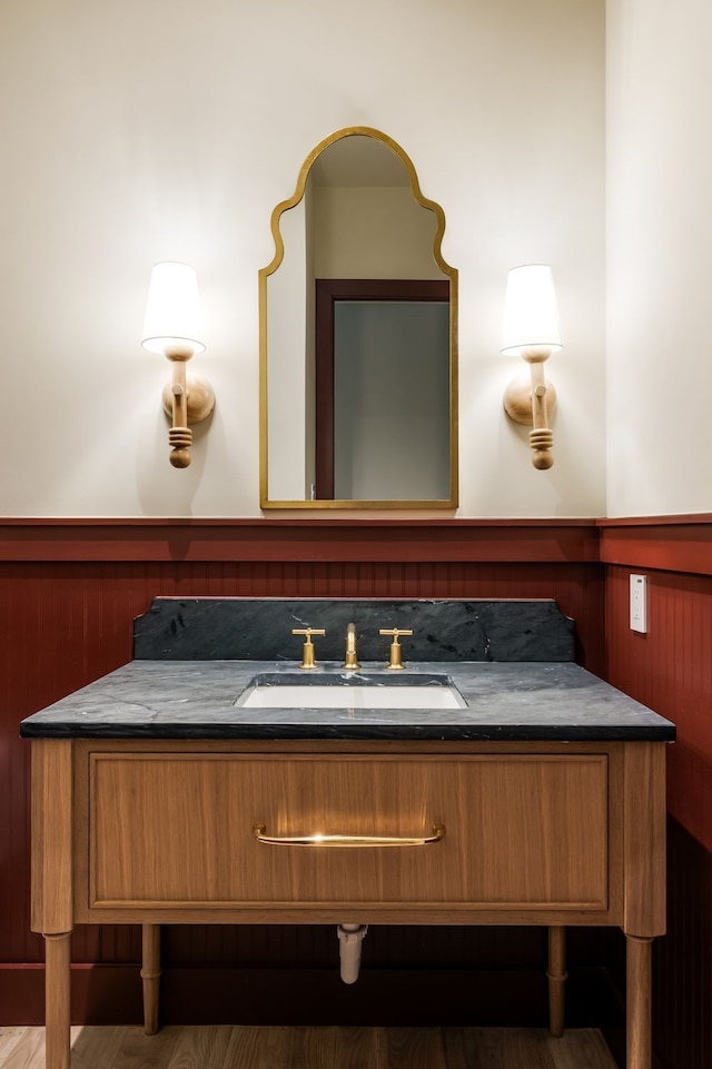 bathroom with wood walls, hardwood / wood-style floors, and vanity