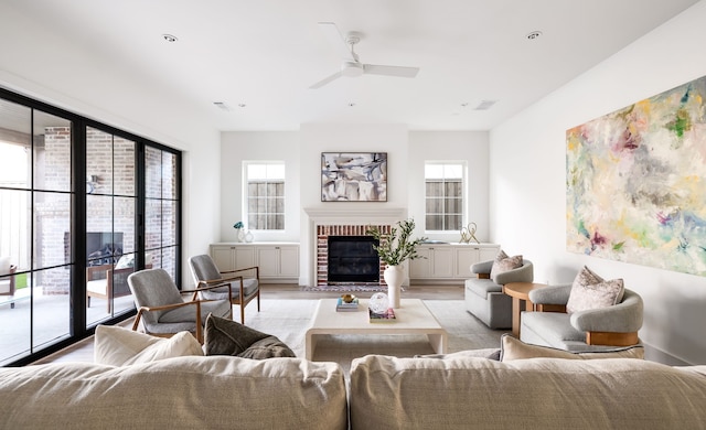 living room with a fireplace, light hardwood / wood-style floors, and ceiling fan