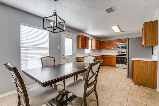 dining area featuring light tile patterned flooring, sink, a textured ceiling, and an inviting chandelier