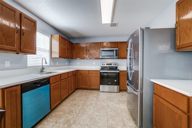 kitchen with appliances with stainless steel finishes, a textured ceiling, light tile patterned floors, and sink