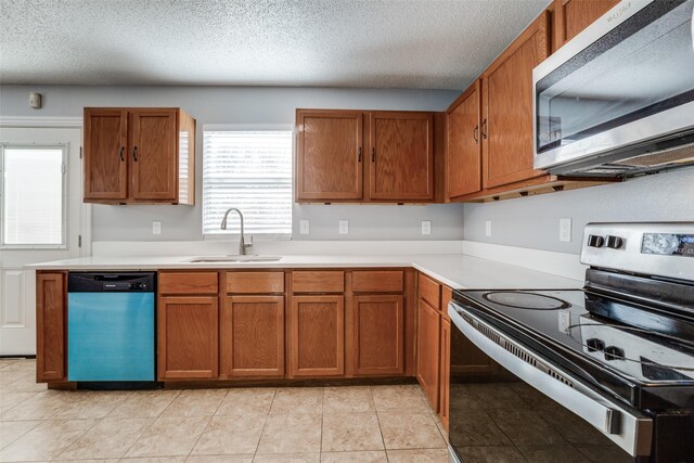 kitchen with sink, light tile patterned floors, stainless steel appliances, and a textured ceiling