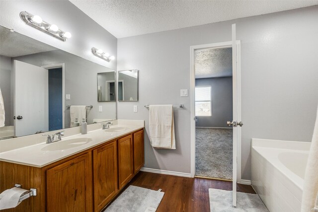 bathroom featuring a bathtub, hardwood / wood-style floors, vanity, and a textured ceiling