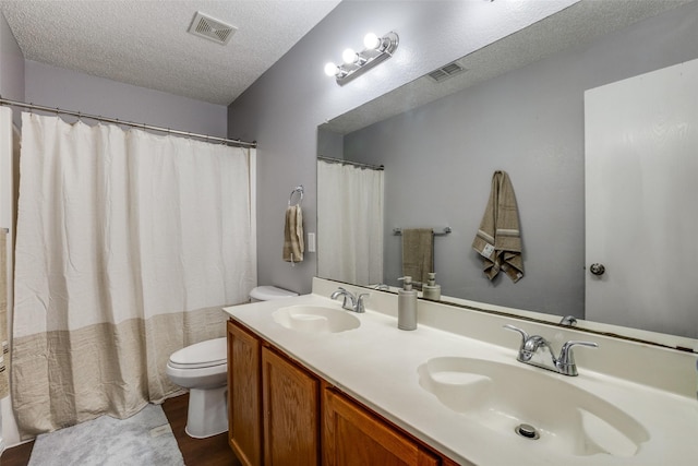 bathroom with hardwood / wood-style floors, vanity, toilet, and a textured ceiling