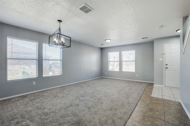 empty room featuring light colored carpet, a textured ceiling, and an inviting chandelier