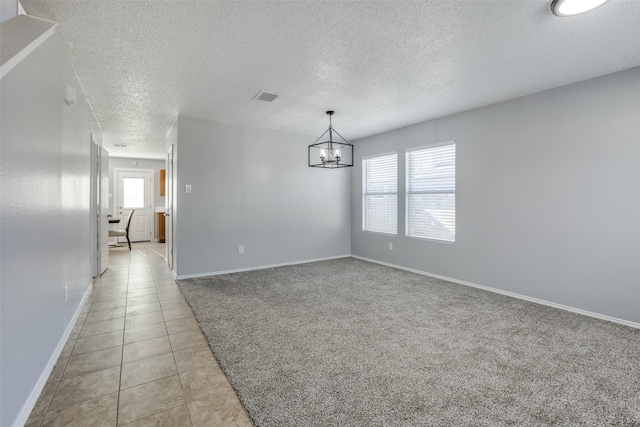 unfurnished room featuring light tile patterned floors, a textured ceiling, and a chandelier