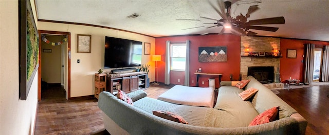 living room featuring crown molding, wood-type flooring, a stone fireplace, and a textured ceiling