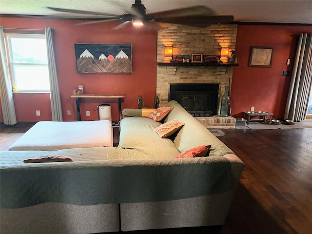 living room featuring ceiling fan, hardwood / wood-style floors, and a brick fireplace