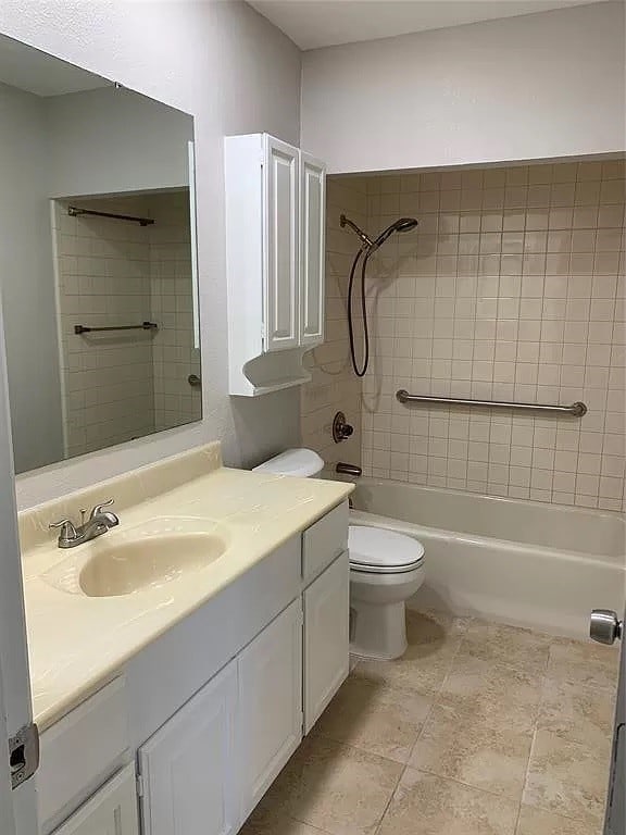 full bathroom featuring vanity, tiled shower / bath combo, and toilet