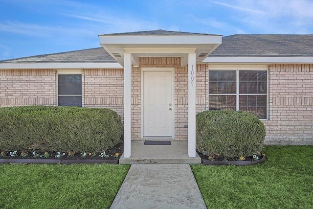 view of exterior entry featuring a lawn