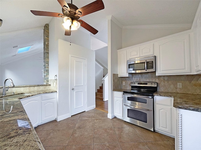 817 Foxridge Dr, Arlington, TX 76017 - kitchen featuring stainless steel appliances, lofted ceiling, tasteful backsplash, white cabinets, and light tile patterned floors