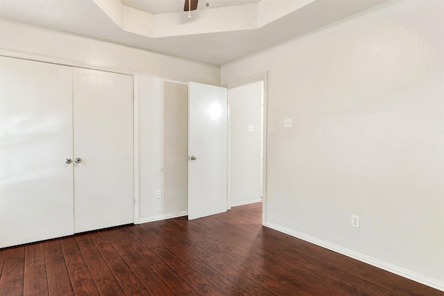 unfurnished bedroom with ceiling fan, dark hardwood / wood-style flooring, and a closet