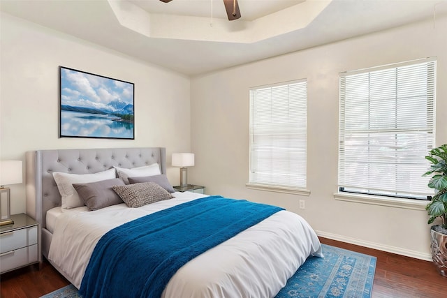 bedroom with ceiling fan, dark hardwood / wood-style floors, and a raised ceiling