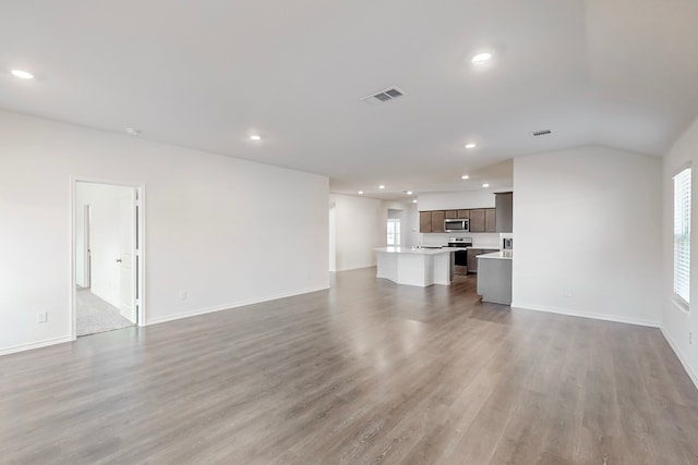 unfurnished living room featuring wood-type flooring and lofted ceiling