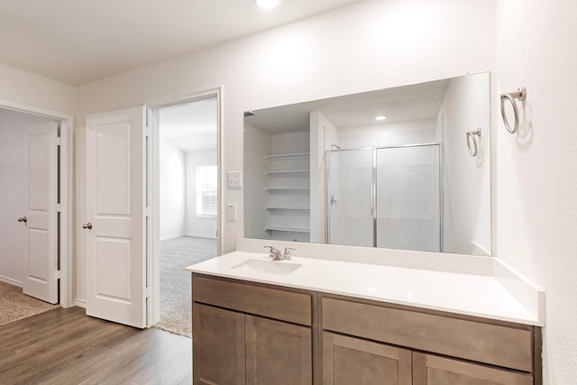 bathroom with hardwood / wood-style flooring, vanity, and a shower with door