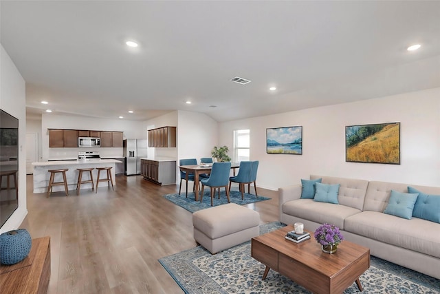 living room with light hardwood / wood-style floors and vaulted ceiling