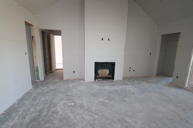 unfurnished living room featuring vaulted ceiling and a wood stove