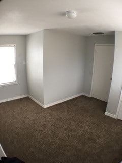 spare room with dark carpet