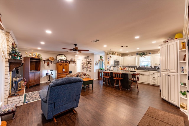 living room with dark hardwood / wood-style flooring, sink, crown molding, and ceiling fan