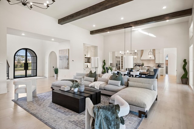 living room with beam ceiling, french doors, and a notable chandelier