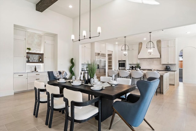 dining area with light tile patterned floors, a high ceiling, and beam ceiling