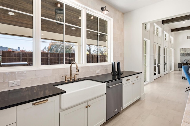 kitchen featuring stainless steel dishwasher, decorative backsplash, white cabinetry, and sink