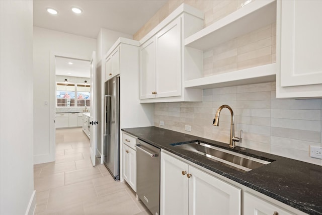 kitchen with white cabinetry, sink, stainless steel appliances, dark stone counters, and decorative backsplash