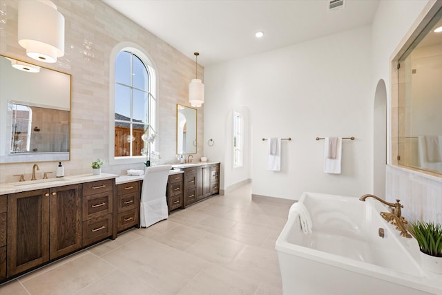 bathroom featuring tile patterned flooring, a bath, vanity, and tile walls