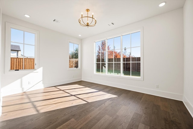 unfurnished dining area featuring dark hardwood / wood-style flooring, a healthy amount of sunlight, and a notable chandelier