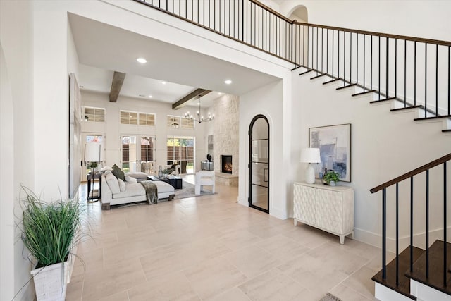 interior space featuring beam ceiling, a stone fireplace, french doors, and a high ceiling