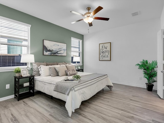 bedroom with light wood-type flooring, visible vents, ceiling fan, and baseboards