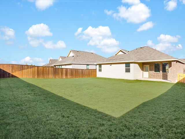 back of house with brick siding, a yard, and a fenced backyard