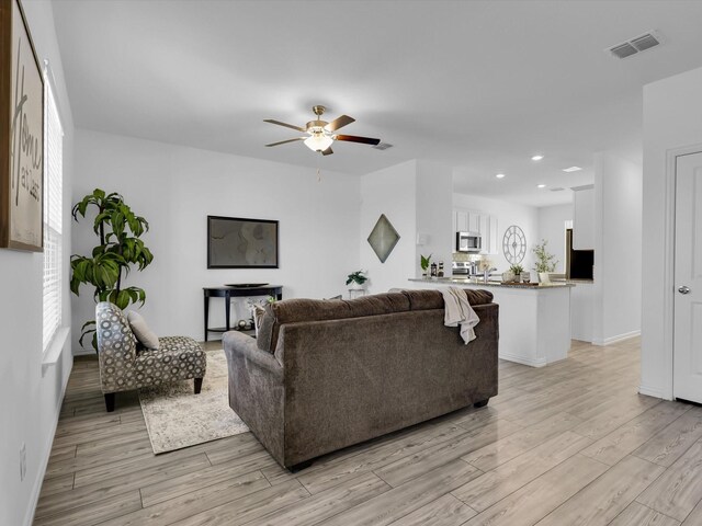 living room with wood-type flooring and ceiling fan