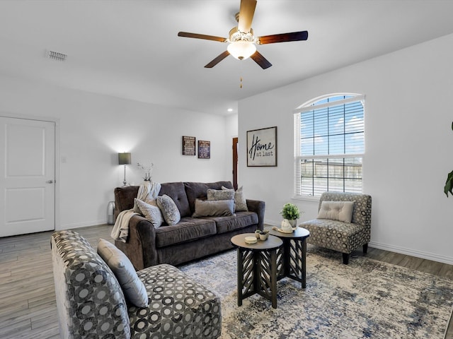 living room featuring light wood-style flooring, visible vents, ceiling fan, and baseboards