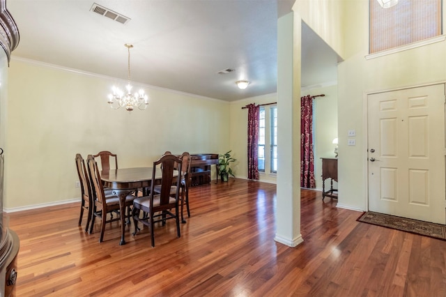 dining area with hardwood / wood-style floors, an inviting chandelier, and ornamental molding