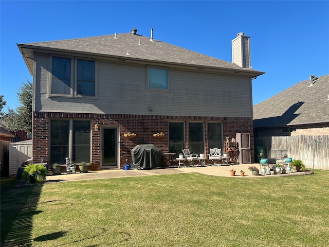 back of house with a lawn, a storage unit, and a patio