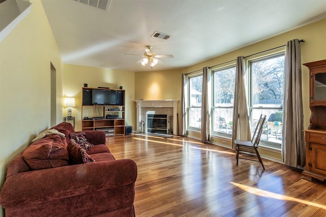 living room featuring a tile fireplace, hardwood / wood-style floors, and ceiling fan