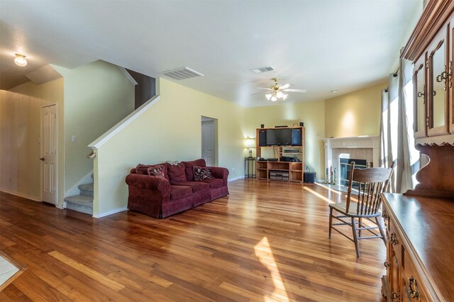 living room featuring ceiling fan, a fireplace, and light hardwood / wood-style floors