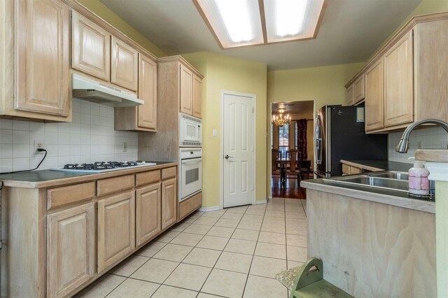 kitchen featuring a notable chandelier, light brown cabinets, white appliances, and backsplash