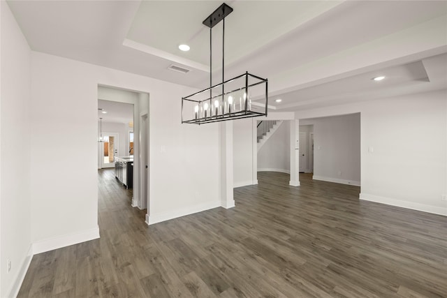 unfurnished dining area featuring a tray ceiling, visible vents, dark wood finished floors, and stairway