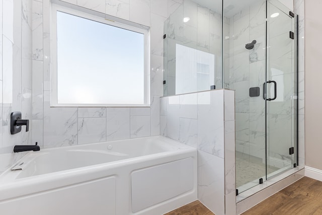 bathroom featuring wood-type flooring and shower with separate bathtub