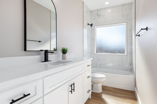 full bathroom with hardwood / wood-style floors, vanity, toilet, and tiled shower / bath