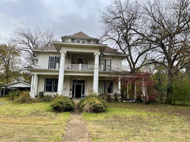 neoclassical home with a balcony and a front lawn