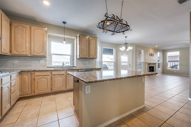 kitchen featuring backsplash, sink, a kitchen island, and light tile patterned floors