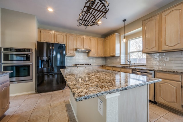 kitchen with light stone countertops, sink, a kitchen island, and appliances with stainless steel finishes