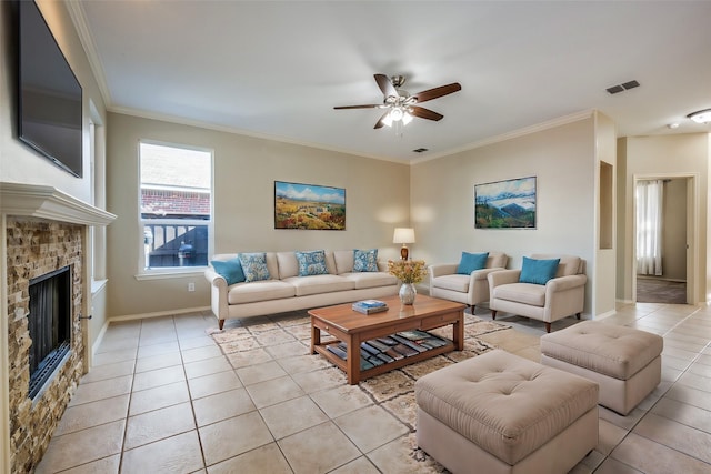 living room featuring ceiling fan, a stone fireplace, ornamental molding, and light tile patterned floors