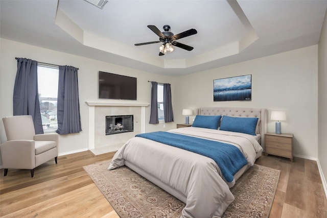 bedroom featuring wood-type flooring, a raised ceiling, and ceiling fan