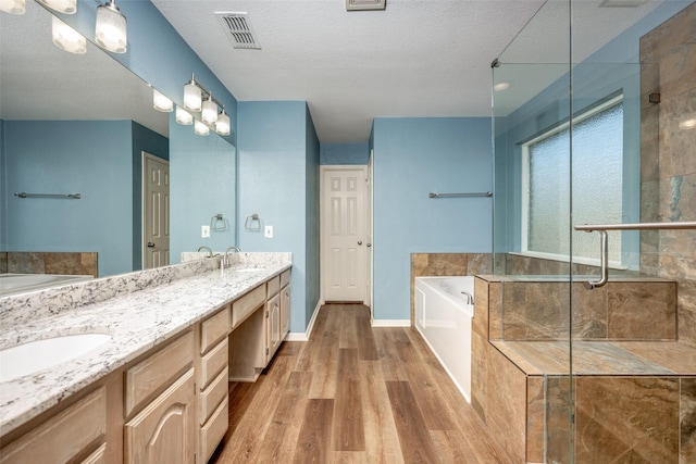 bathroom with vanity, hardwood / wood-style floors, plus walk in shower, and a textured ceiling