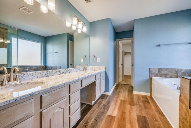 bathroom with a washtub, vanity, and hardwood / wood-style flooring