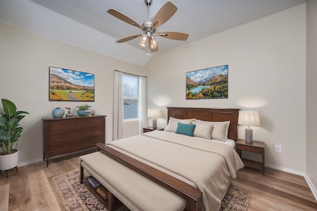 bedroom with ceiling fan, vaulted ceiling, and light wood-type flooring