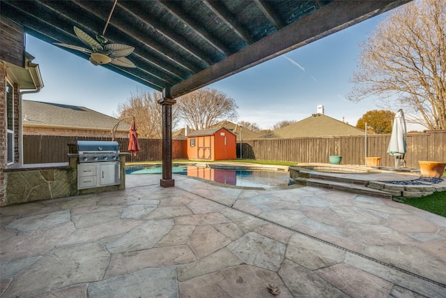 view of patio featuring a swimming pool with hot tub, a shed, exterior kitchen, and a grill